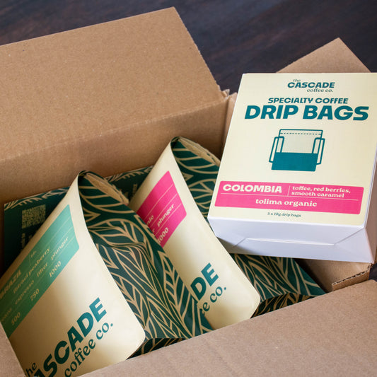 Box of Cascade Coffee Co. coffee bags including a box of drip bags and two coffee packages.